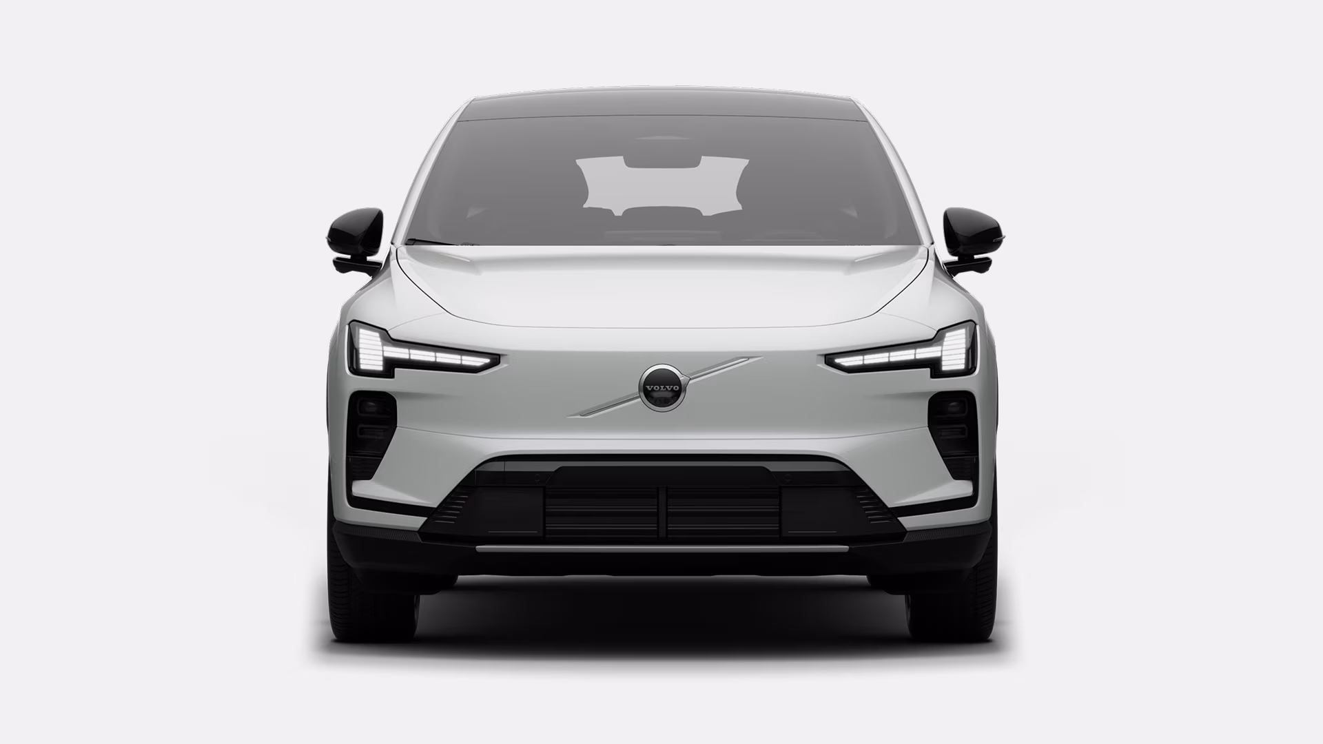 Вид спереди на белый Volvo EX60 с современной решеткой радиатора и фирменными светодиодными фарами.