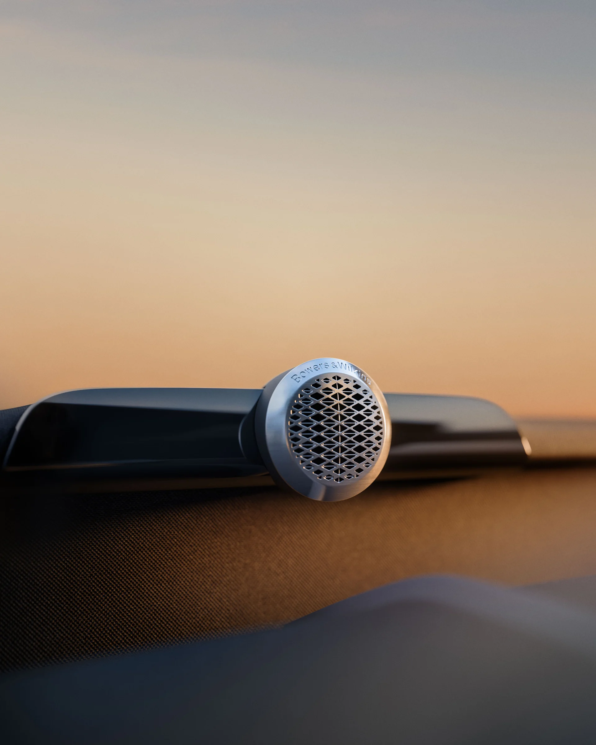Крупный план высокочастотного динамика Bowers & Wilkins, установленного на приборной панели, с теплым вечерним светом.