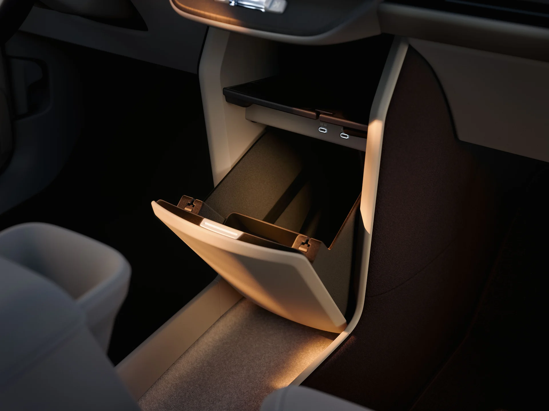 Перчаточный ящик Volvo EX60 с открытой крышкой, расположенный под панелью для беспроводной зарядки телефона и двумя портами USB-C.
