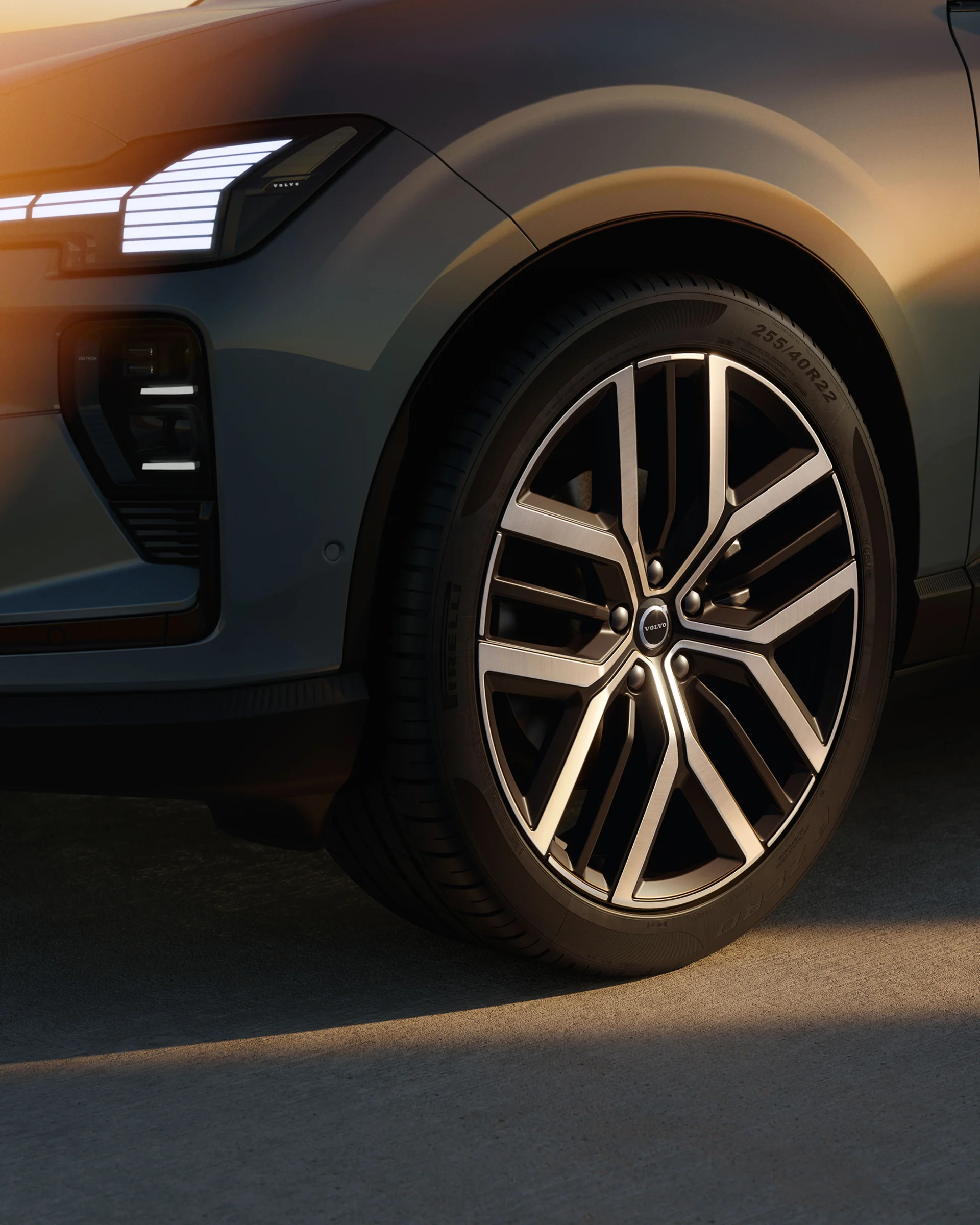 Крупный план переднего колеса Volvo EX60 с характерной фарой в теплом вечернем свете.