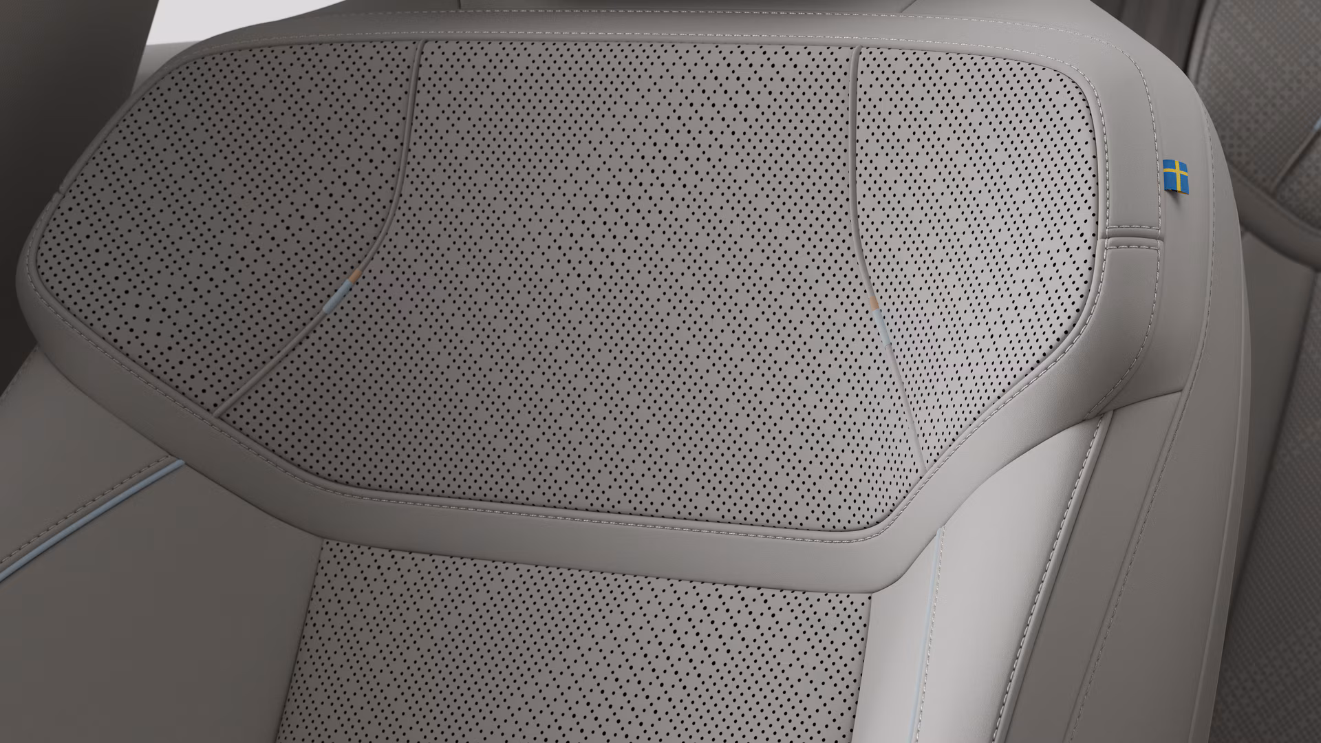 Крупный план деталей салона автомобиля Volvo, на котором видны швы и маленькая бирка с шведским флагом.