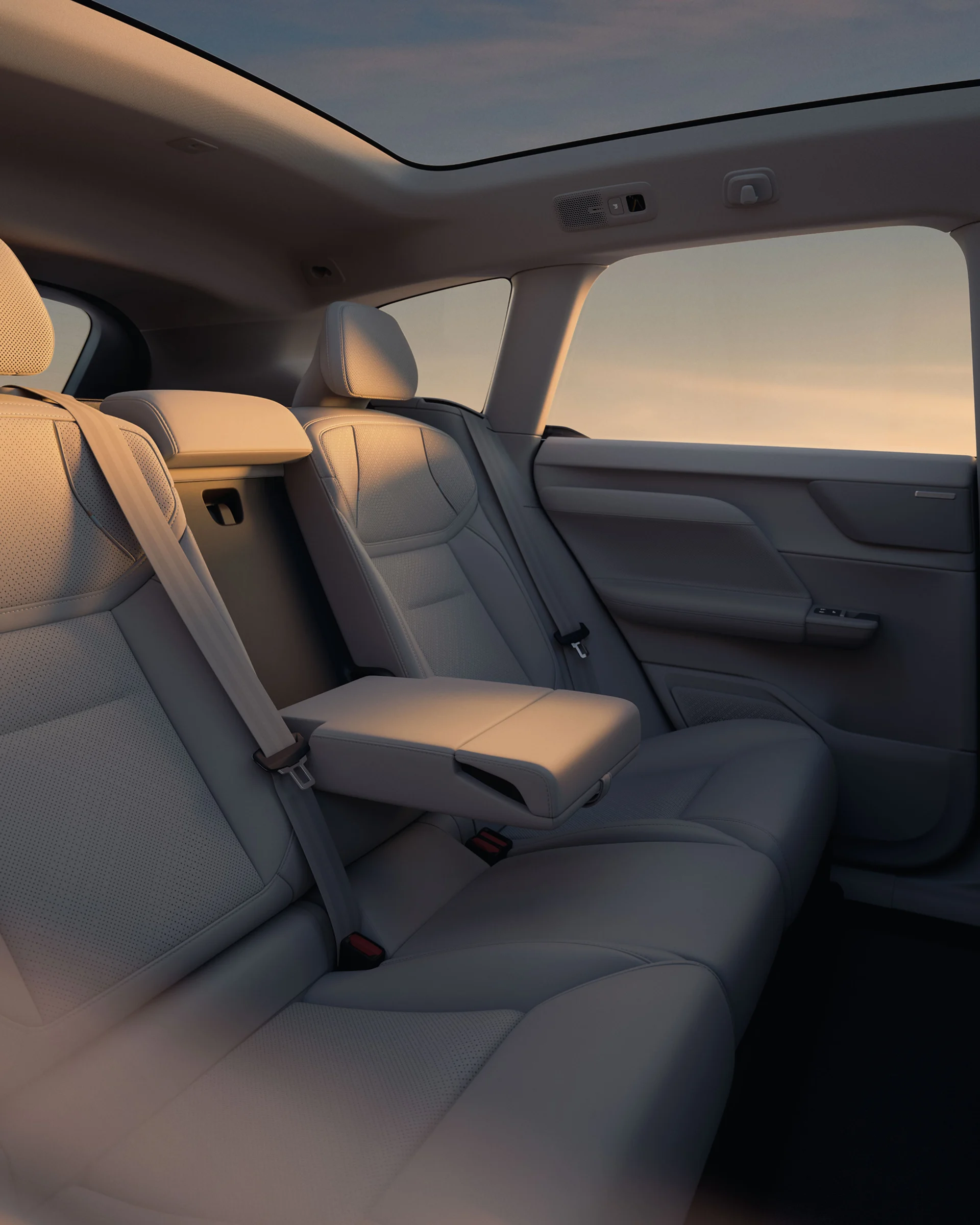 Задние сиденья Volvo EX60 со сложенным центральным подлокотником в теплом вечернем свете.