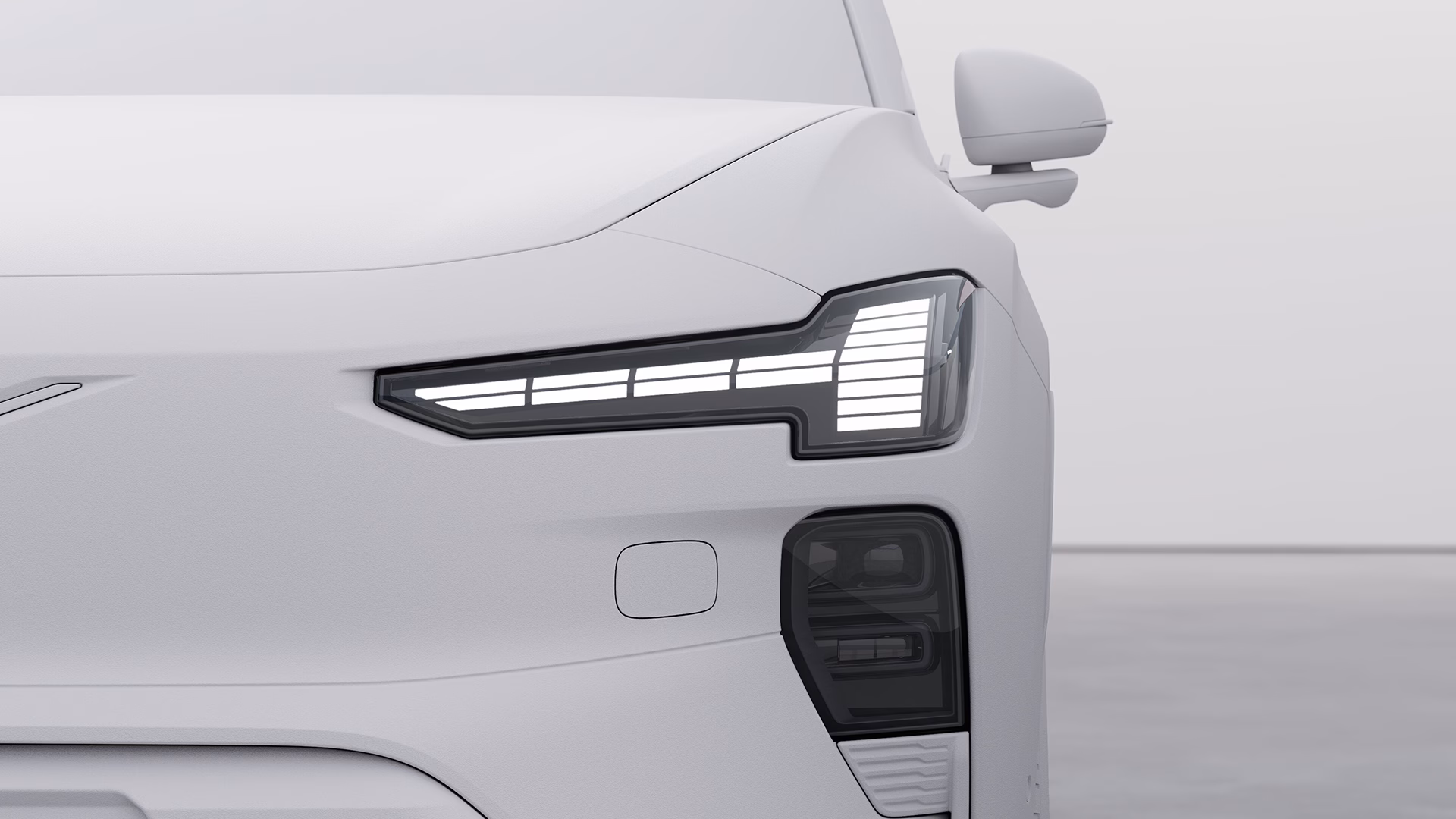 Крупный план передней левой фары и зеркала автомобиля Volvo, демонстрирующий характерный дизайн светодиодной подсветки.