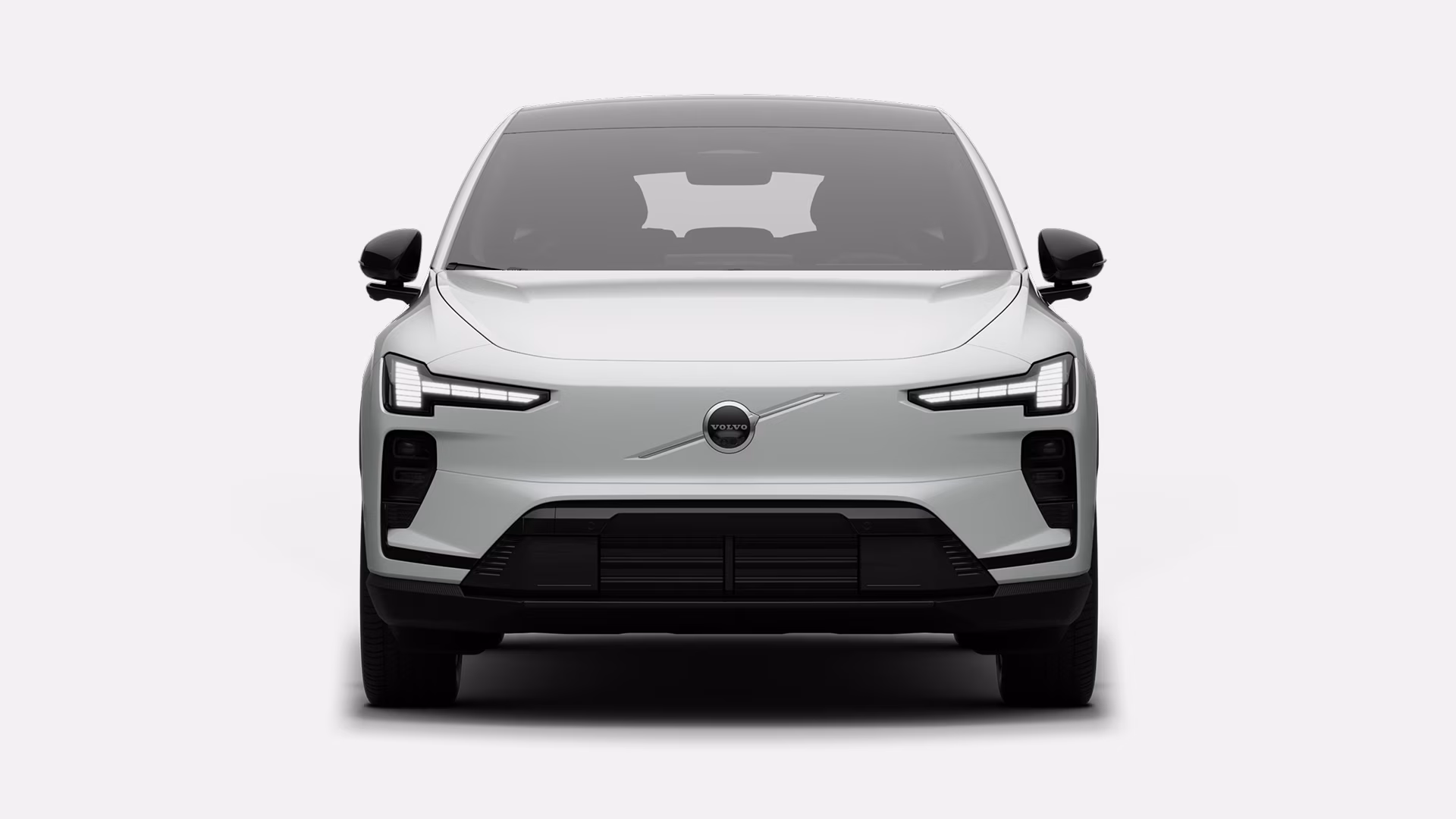 Вид спереди на белый электрический внедорожник Volvo с фирменной решеткой радиатора Volvo и современными светодиодными фарами.