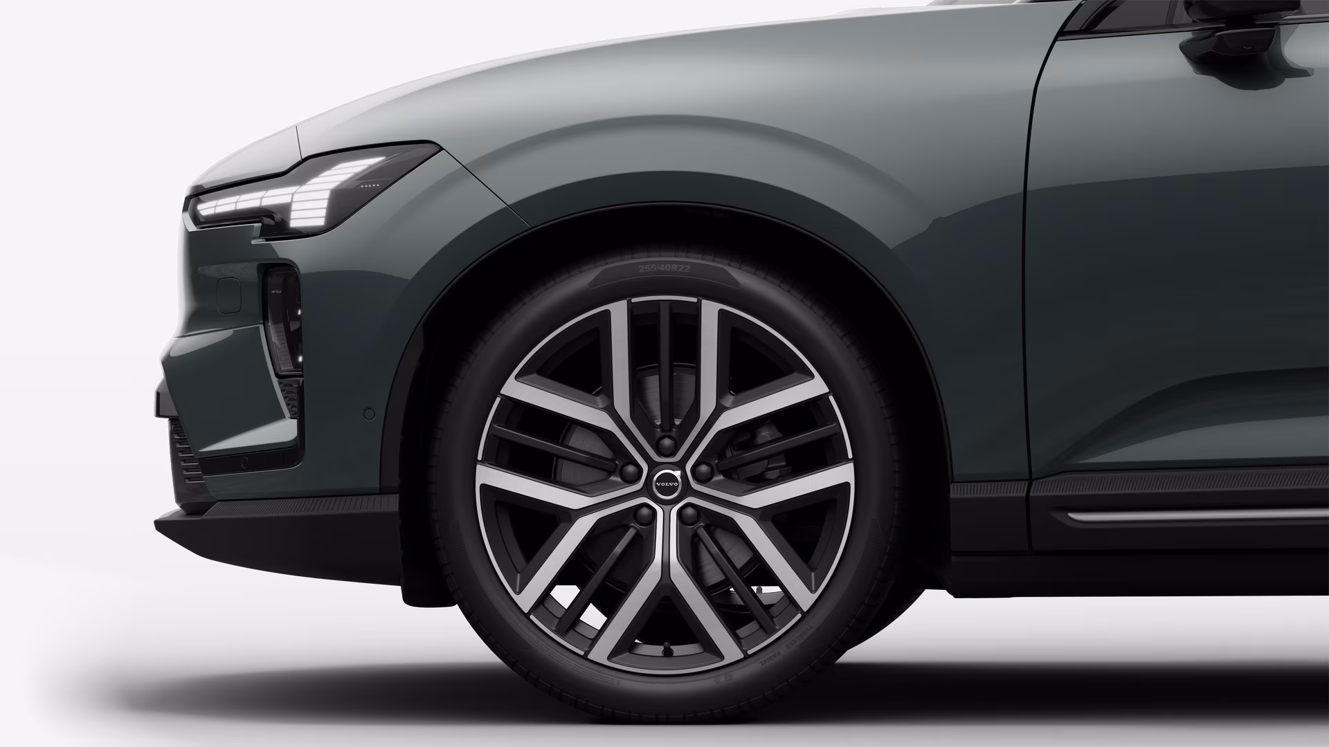 Вид сбоку на переднее колесо и крыло автомобиля Volvo на однотонном студийном фоне.
