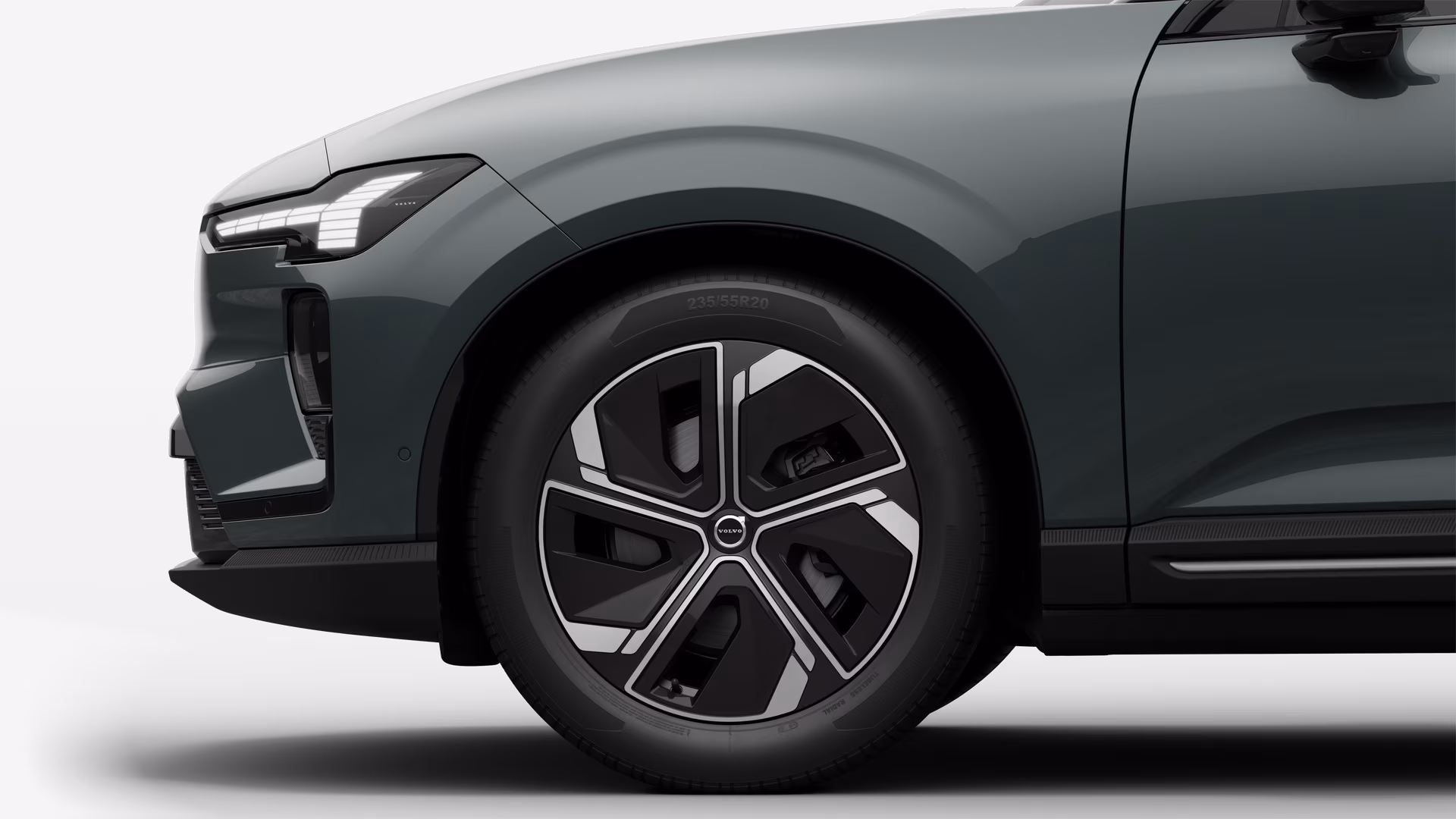 Вид сбоку на переднее колесо и крыло автомобиля Volvo на однотонном студийном фоне.