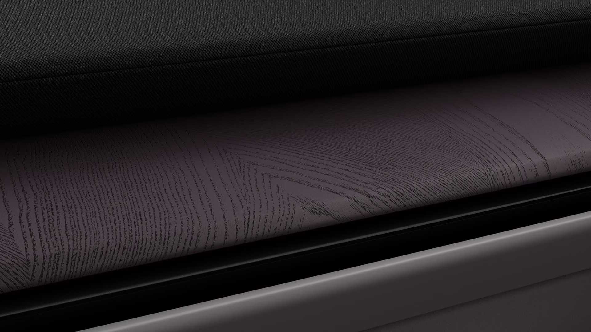 Крупный план салона Volvo с черной текстильной обивкой и отделкой из темного дерева с тонким рисунком текстур.