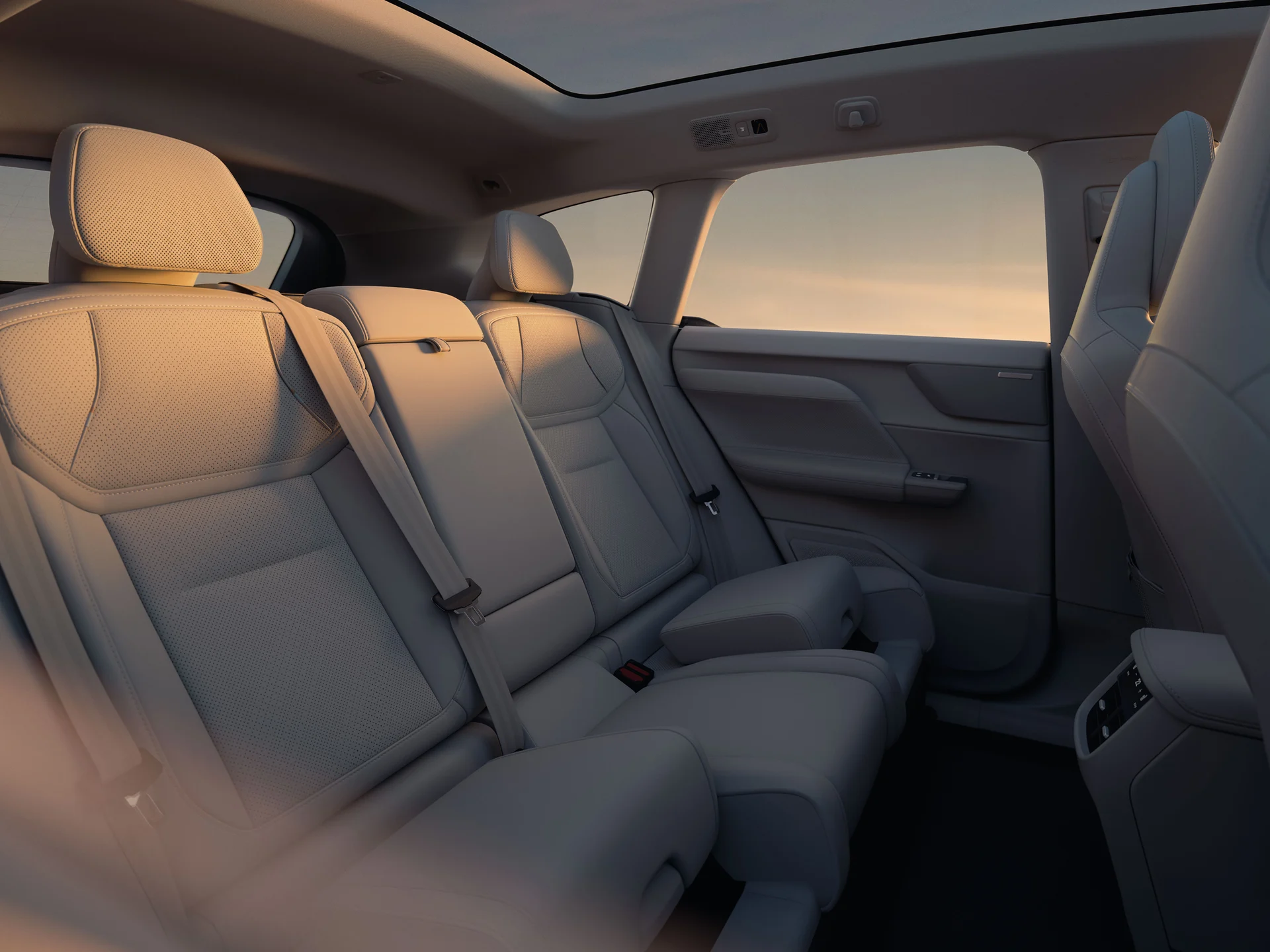 Задние сиденья Volvo EX60 в теплом вечернем свете, встроенный бустер поднят с левой стороны.