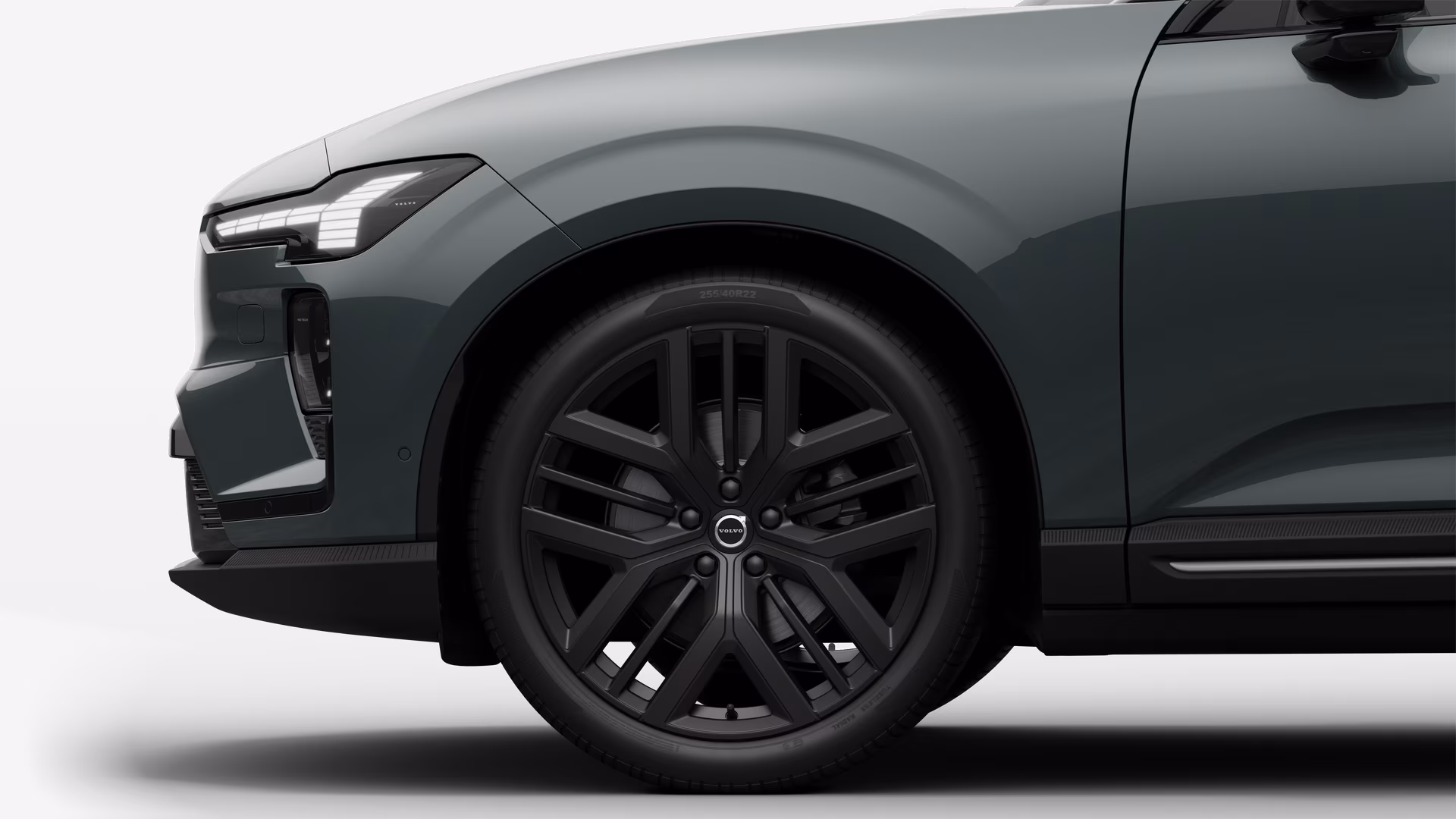 Вид сбоку на переднее колесо и крыло автомобиля Volvo на однотонном студийном фоне.