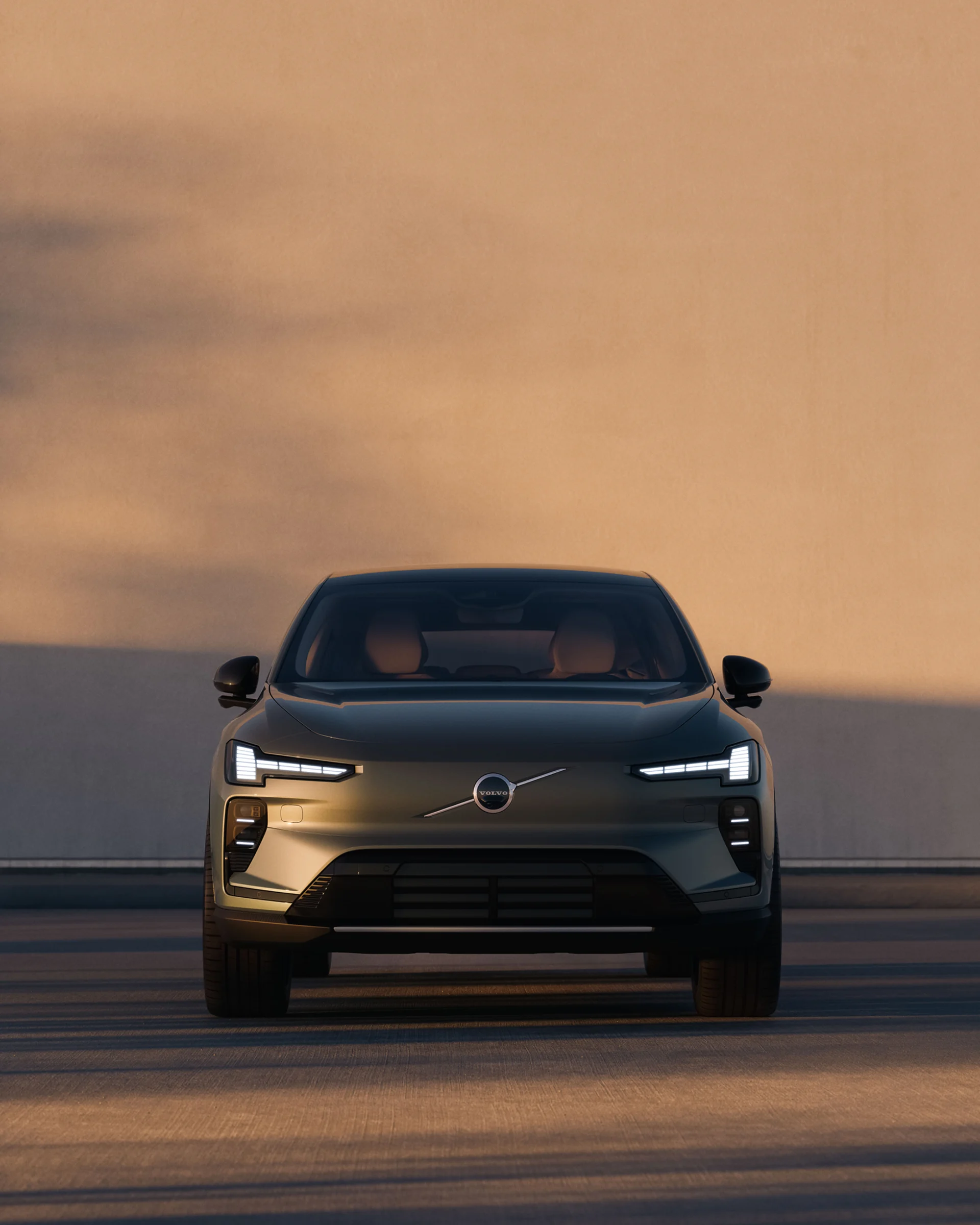Вид спереди на Volvo EX60, припаркованный перед стеной.