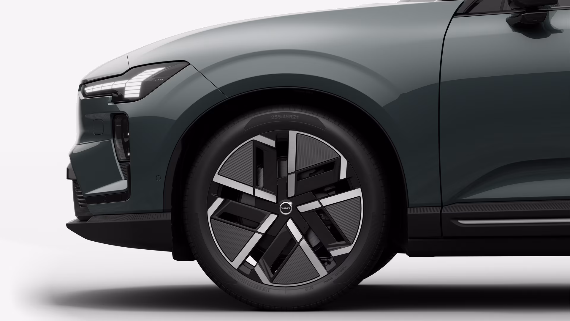 Вид сбоку на переднее колесо и крыло автомобиля Volvo на однотонном студийном фоне.