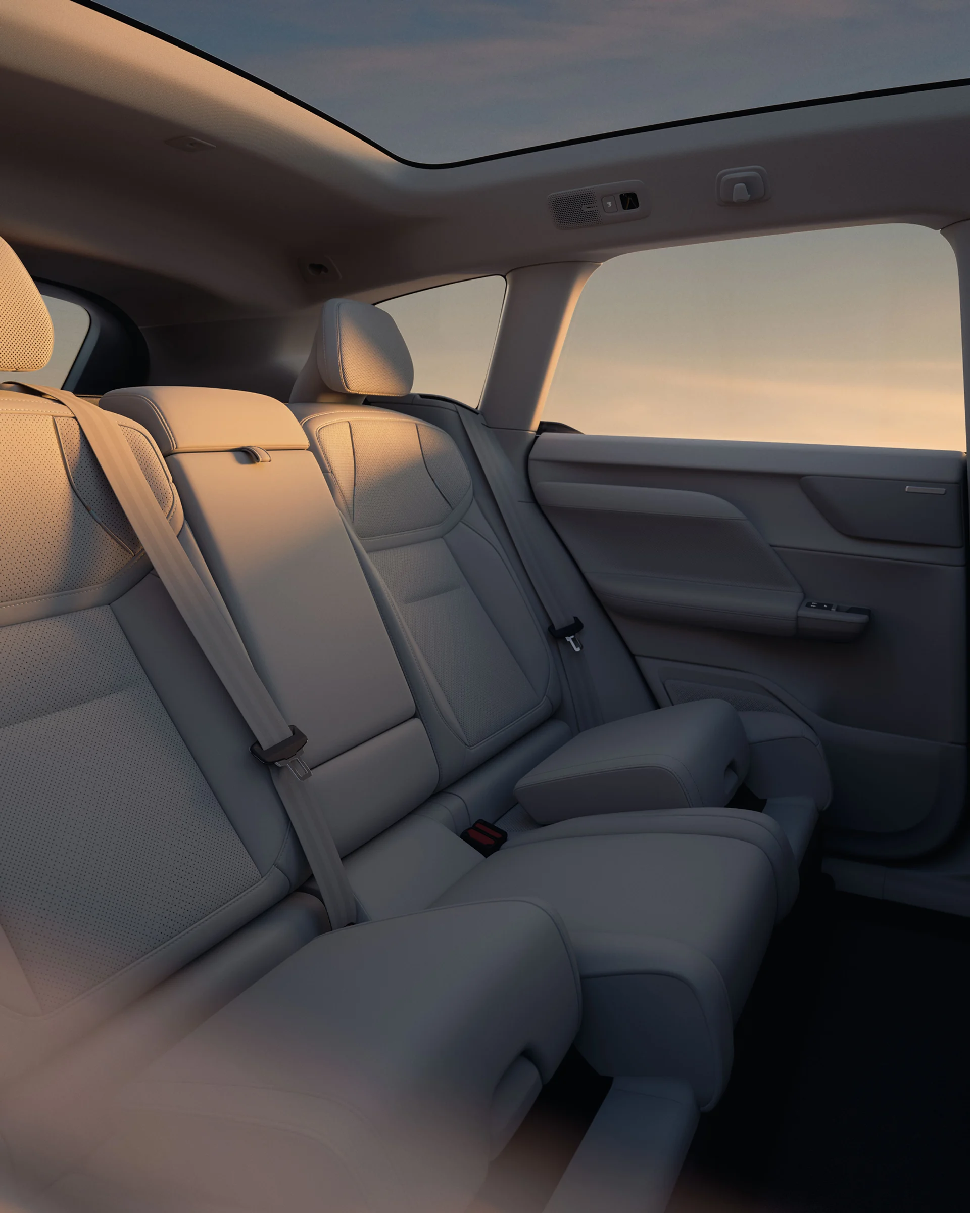 Задние сиденья Volvo EX60 в теплом вечернем свете, встроенный бустер поднят с левой стороны.