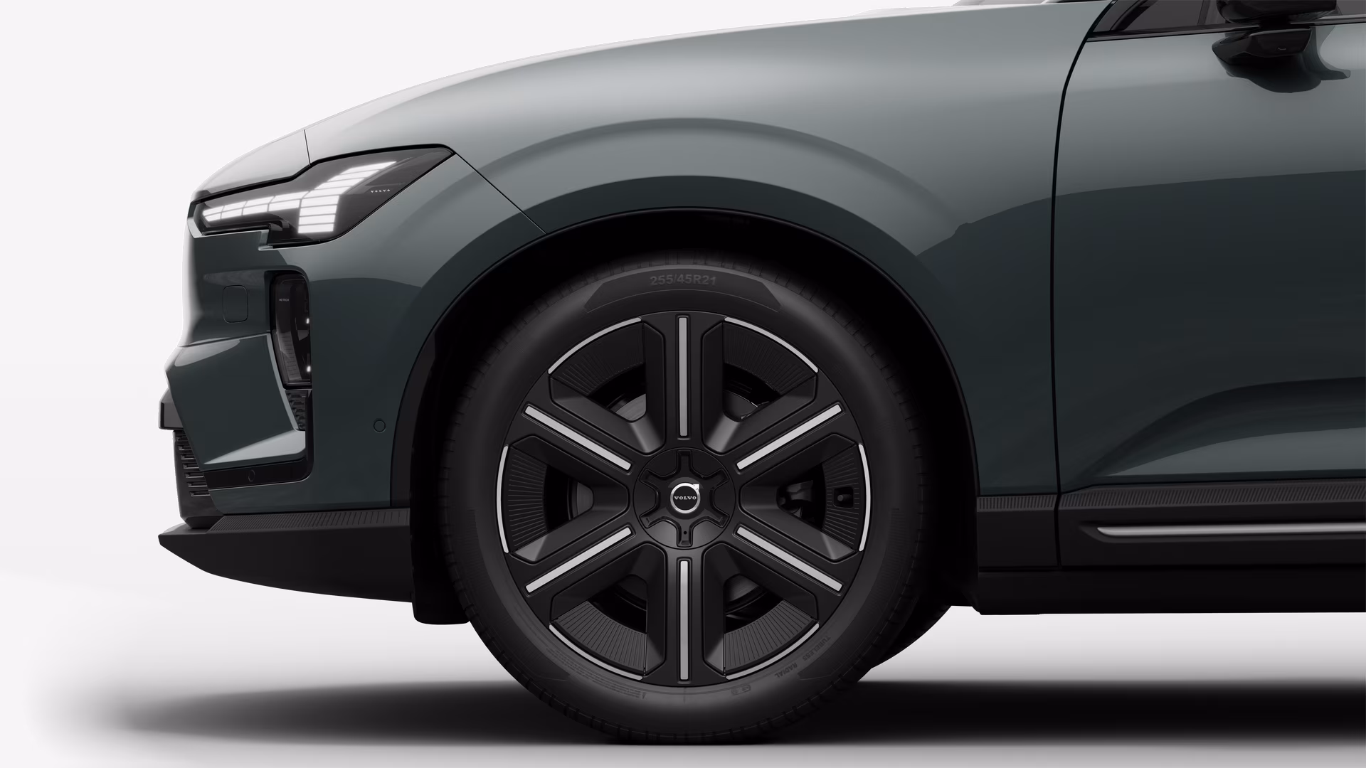 Вид сбоку на переднее колесо и крыло автомобиля Volvo на однотонном студийном фоне.
