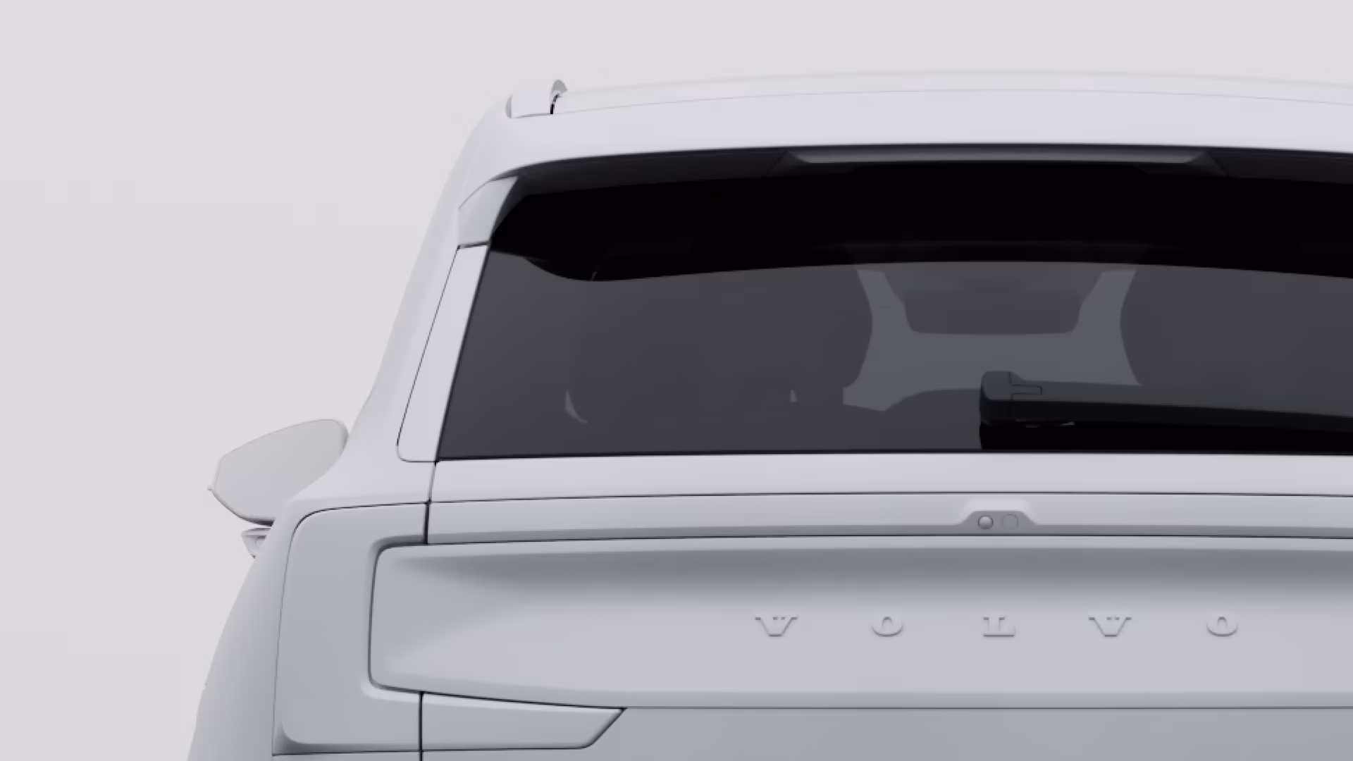 Вид сзади на автомобиль Volvo: заднее стекло, задний стеклоочиститель и надпись Volvo на двери багажника.