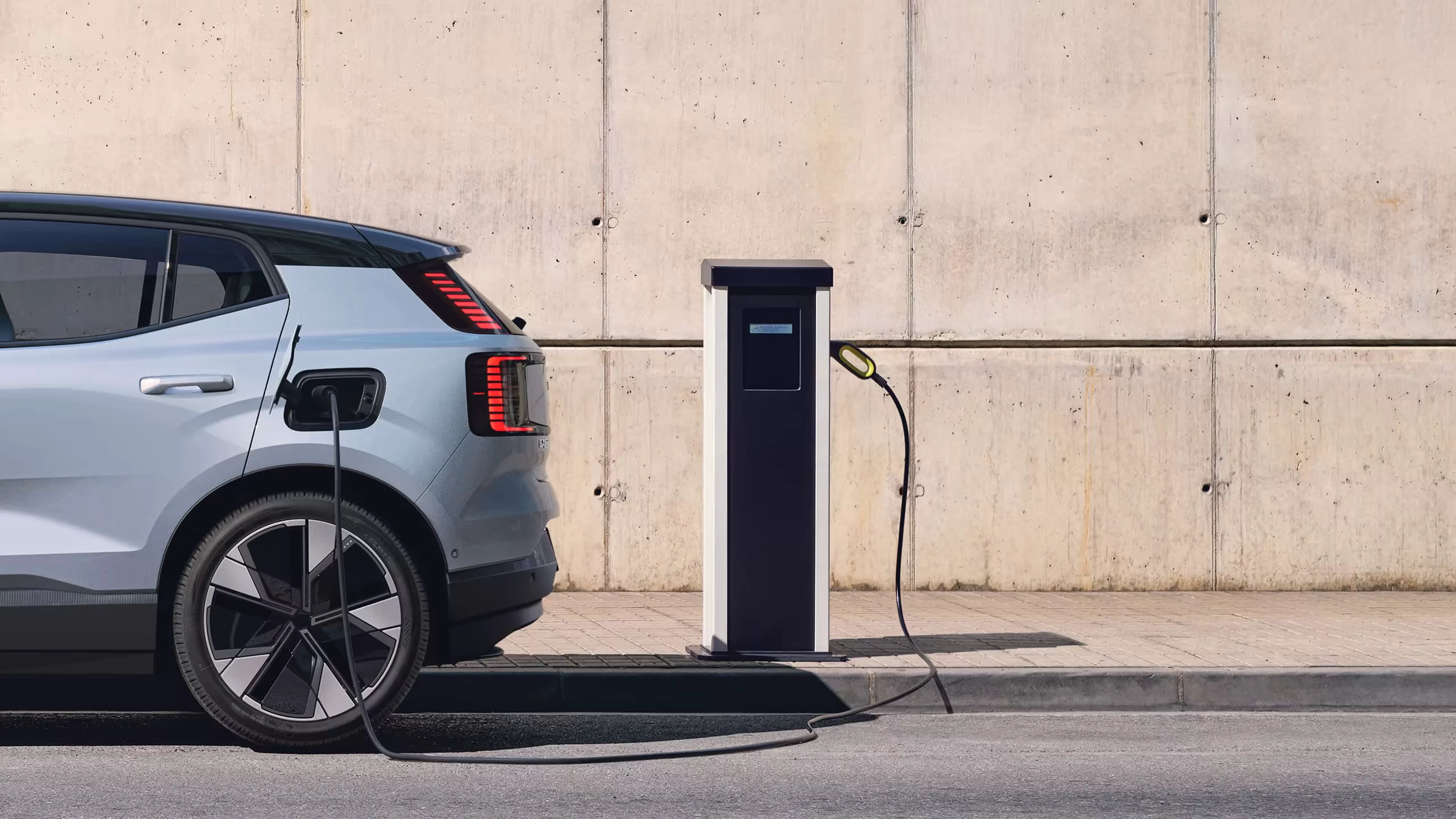 Крупный план Volvo EX30 цвета Небесно-голубой, подключенный к зарядной станции.