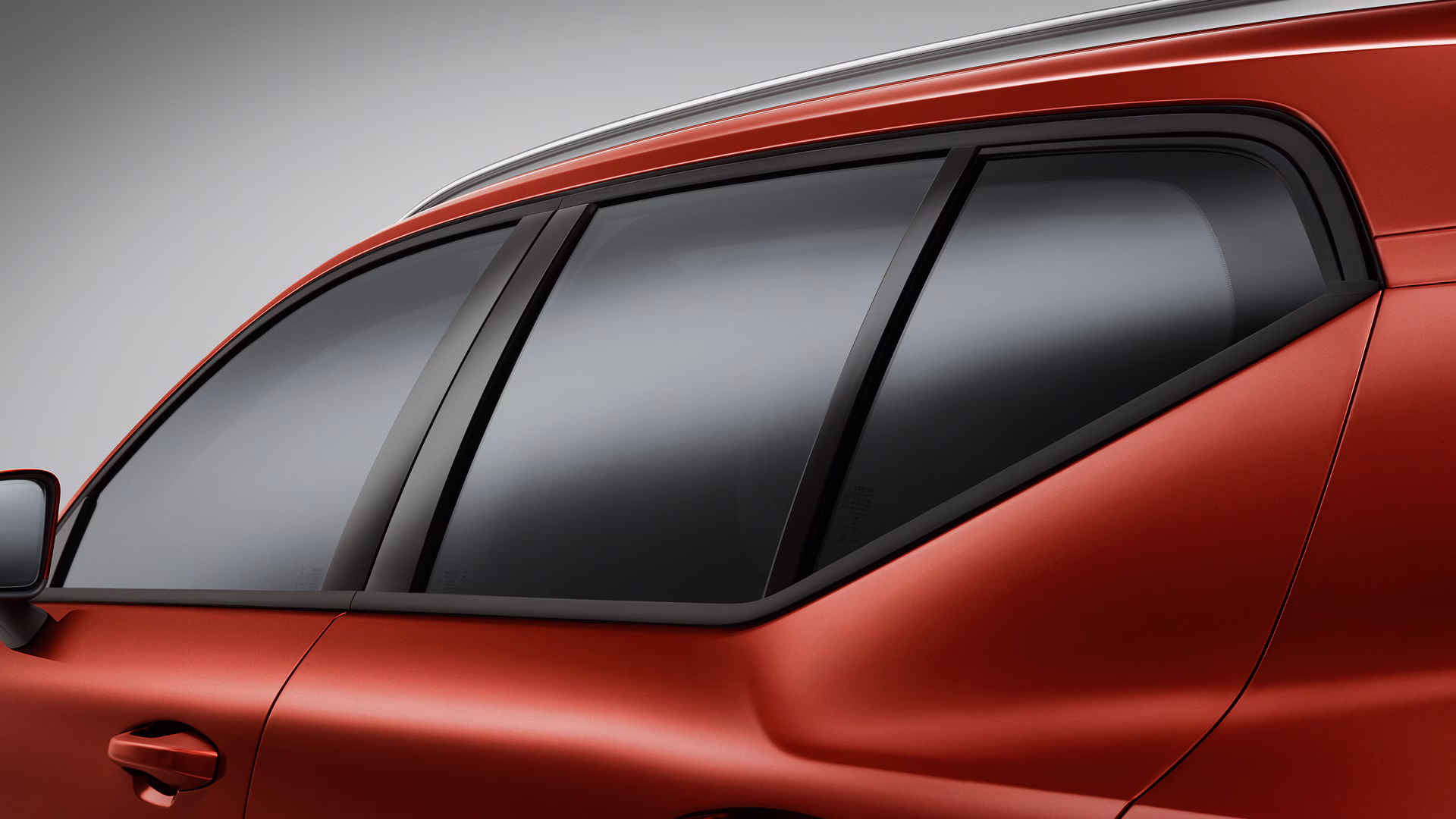 Крупный план заднего бокового окна и двери красного автомобиля Volvo, подчеркивающий дизайн окон и гладкие линии кузова.