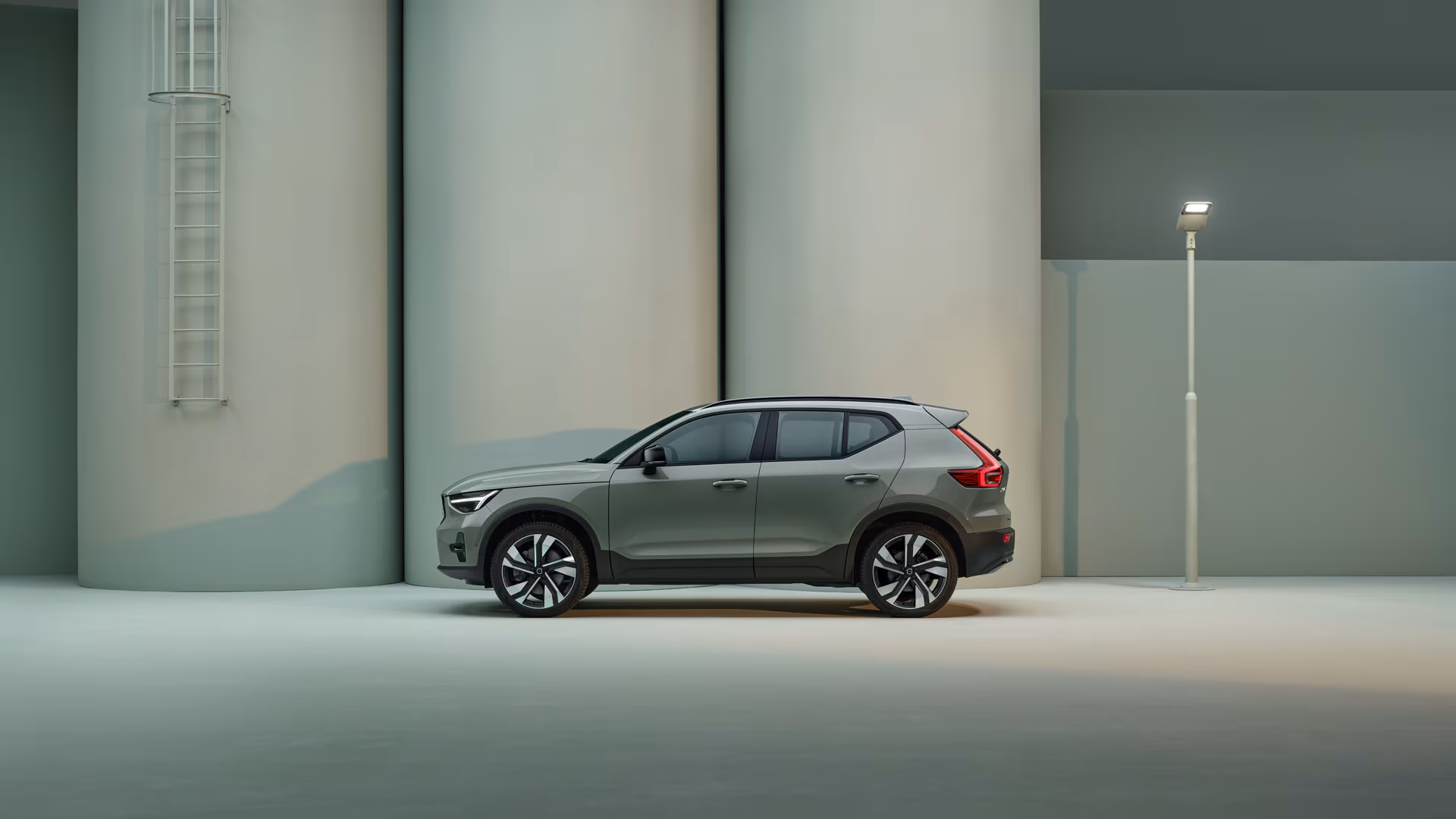Вид сбоку на Volvo XC40, припаркованный в минималистичной современной обстановке с мягким освещением.