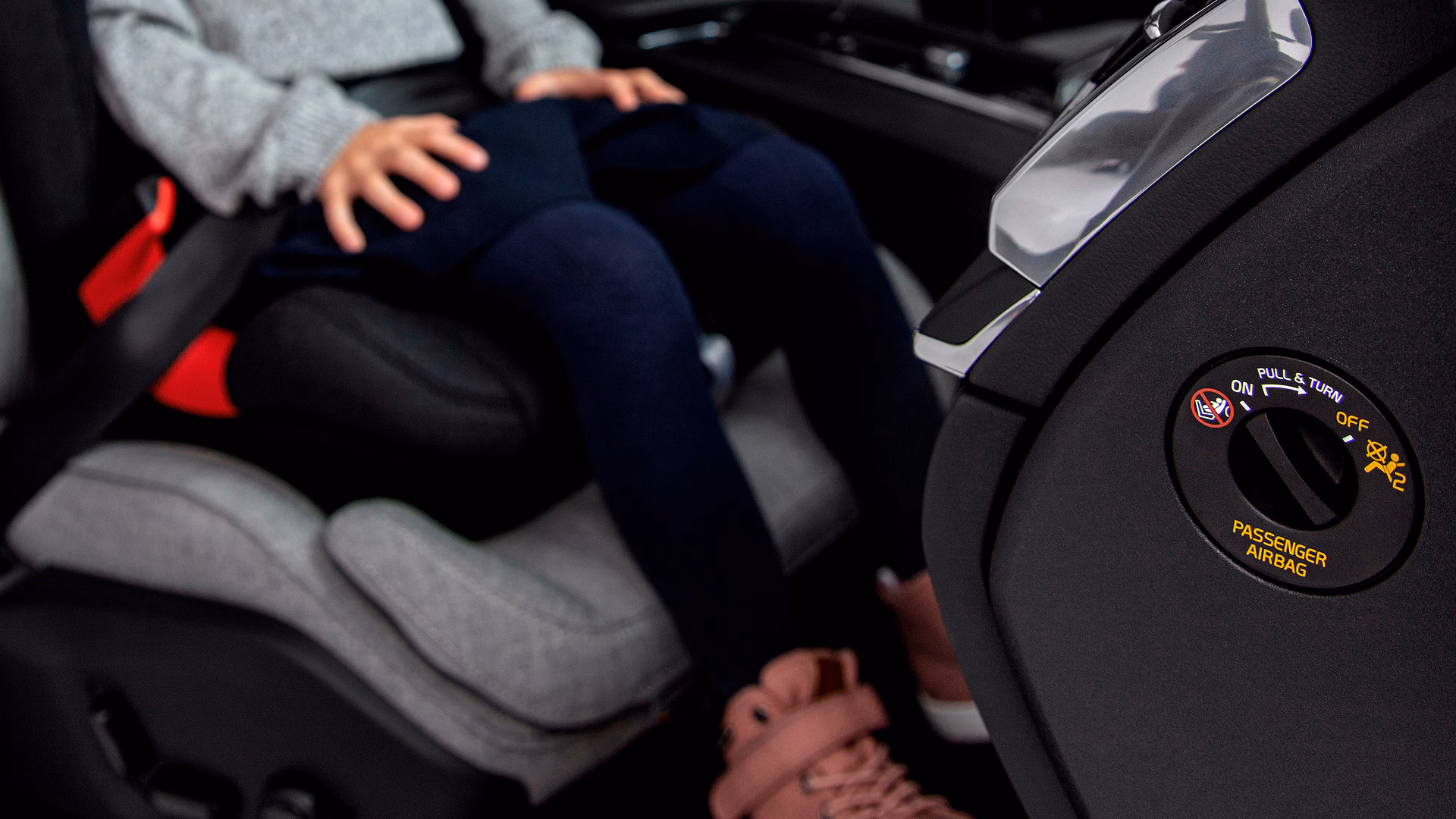 Ребенок, сидящий в бустерном кресле автомобиля Volvo с видимым переключателем управления подушкой безопасности пассажира на приборной панели.