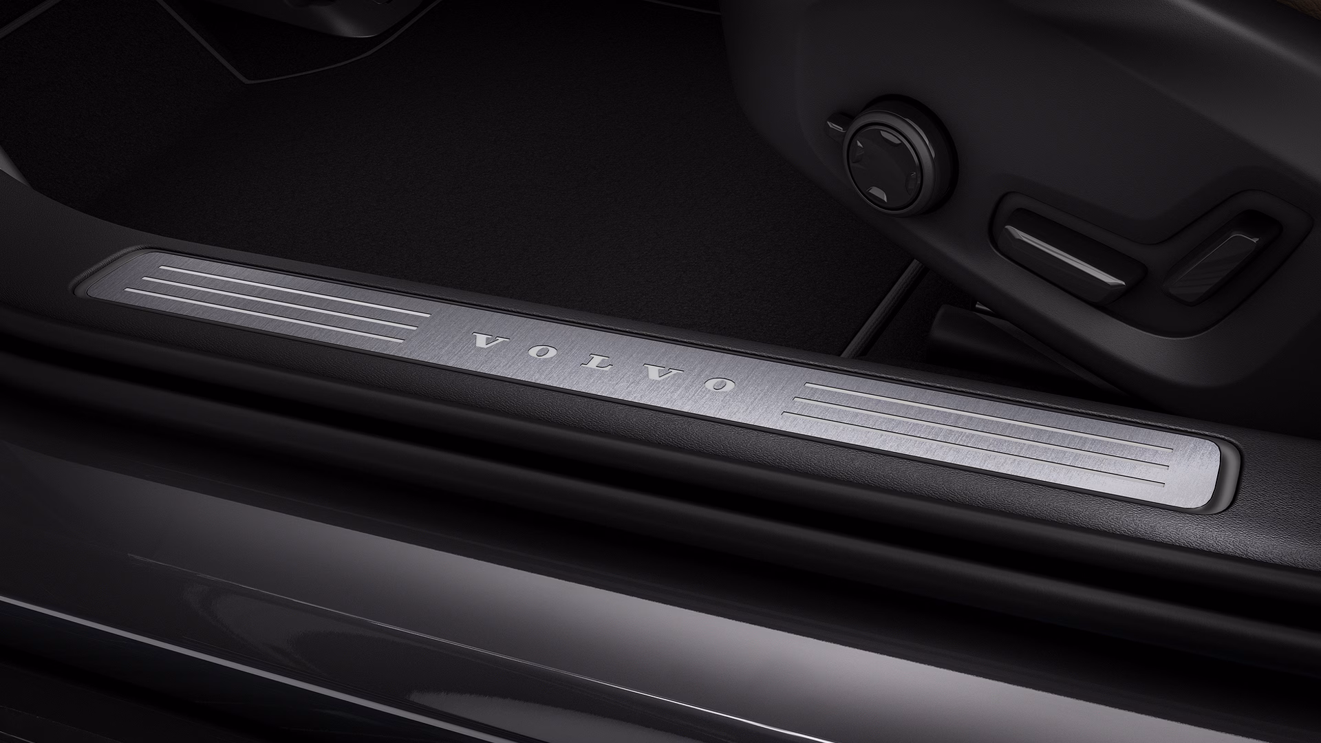 Крупный план накладки порога автомобиля Volvo с логотипом Volvo, выгравированным на матовом металле.