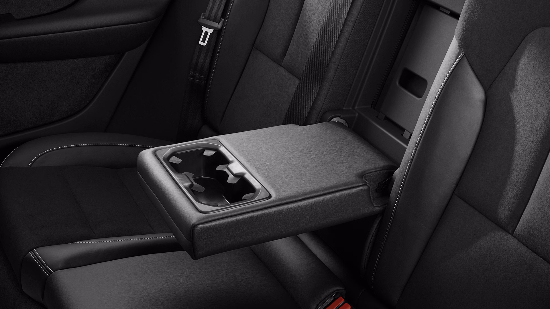 Крупный план центрального подлокотника заднего сиденья в автомобиле Volvo со встроенными подстаканниками.