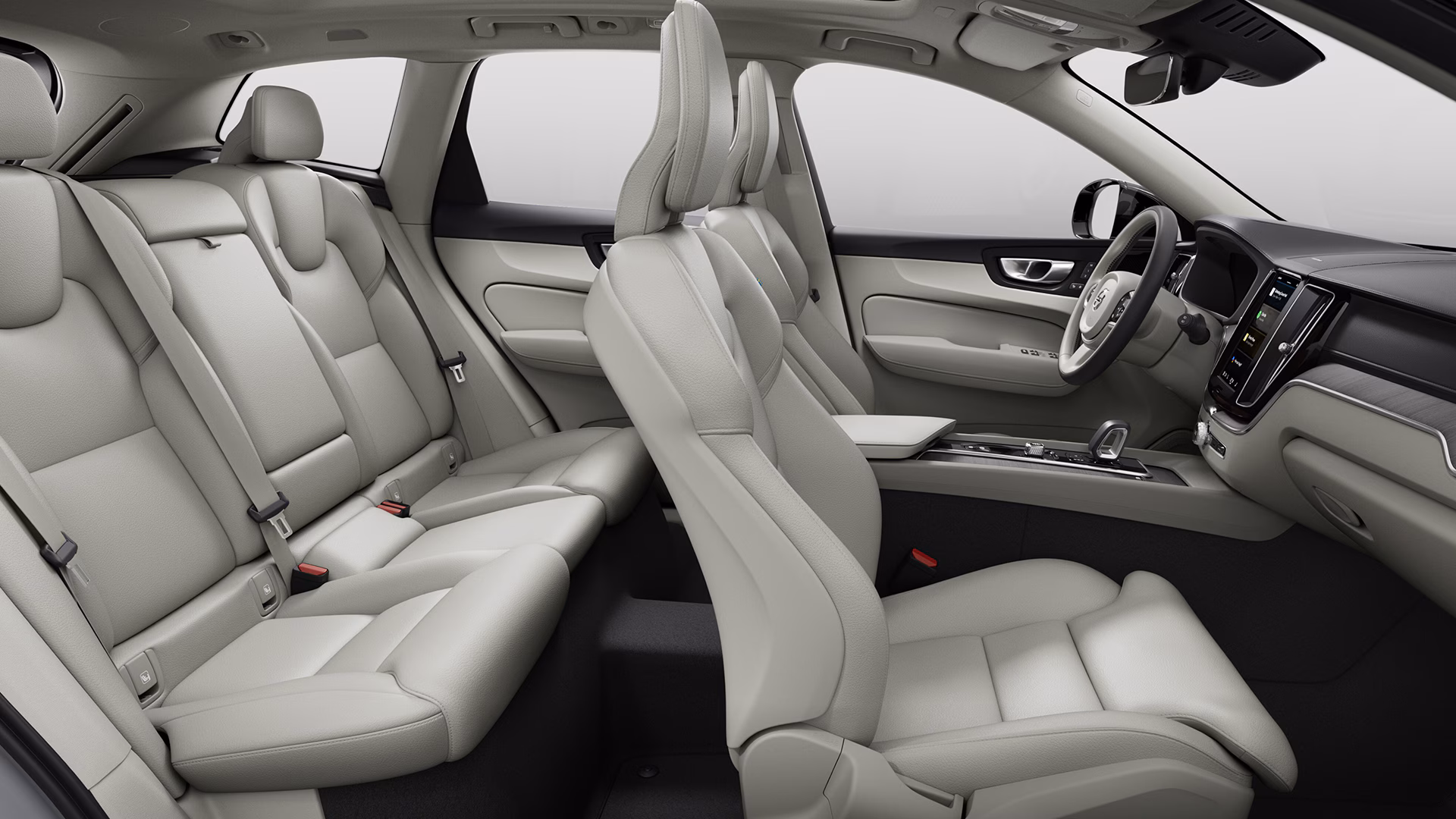 Вид изнутри автомобиля Volvo со светлыми кожаными сиденьями, просторными задними и передними сиденьями, а также современной приборной панелью с центральным сенсорным дисплеем.