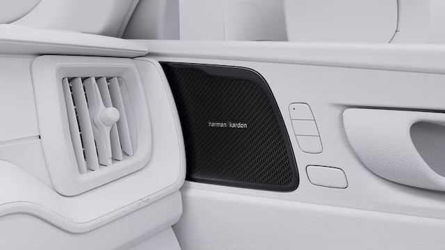 Крупный план внутренней дверной панели автомобиля Volvo с решеткой динамика Harman Kardon и вентиляционным отверстием.