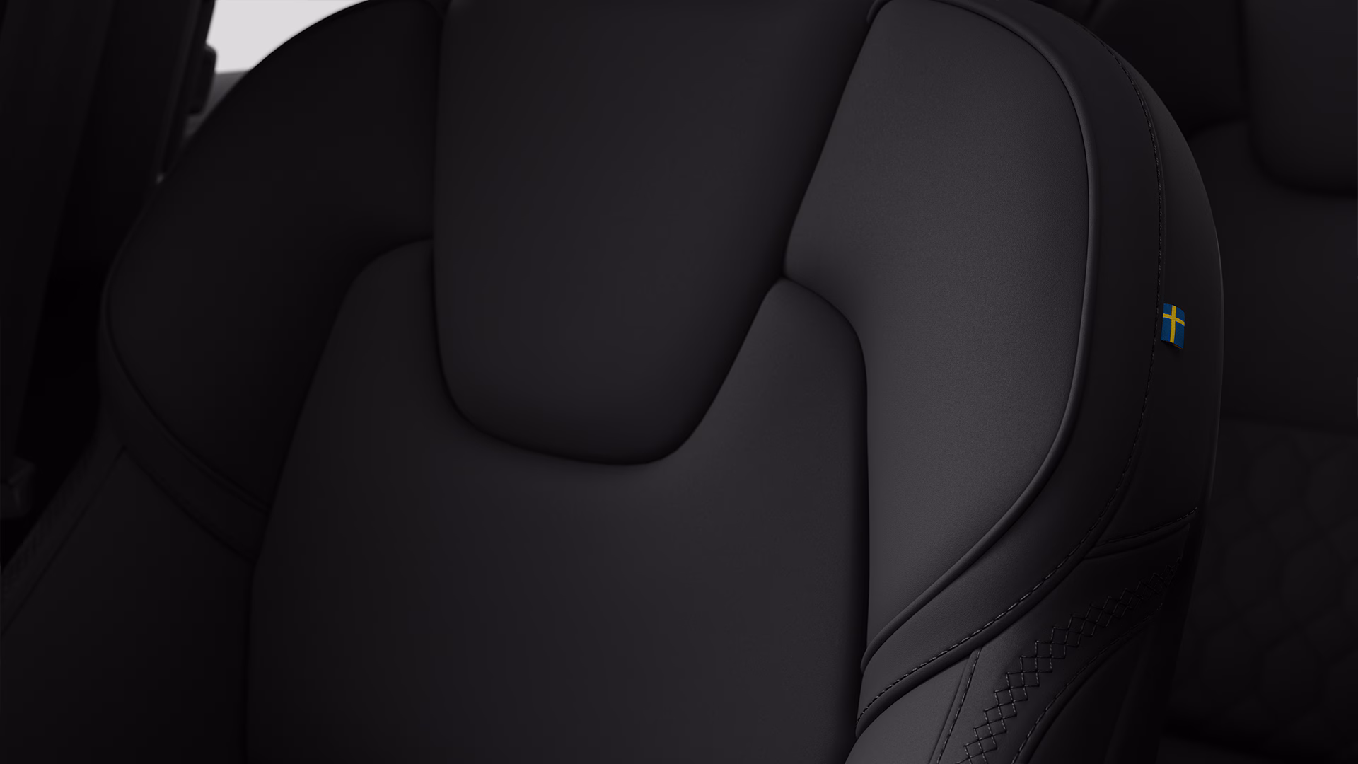 Крупный план автомобильного сиденья Volvo в черной обивке с небольшой биркой со шведским флагом сбоку.