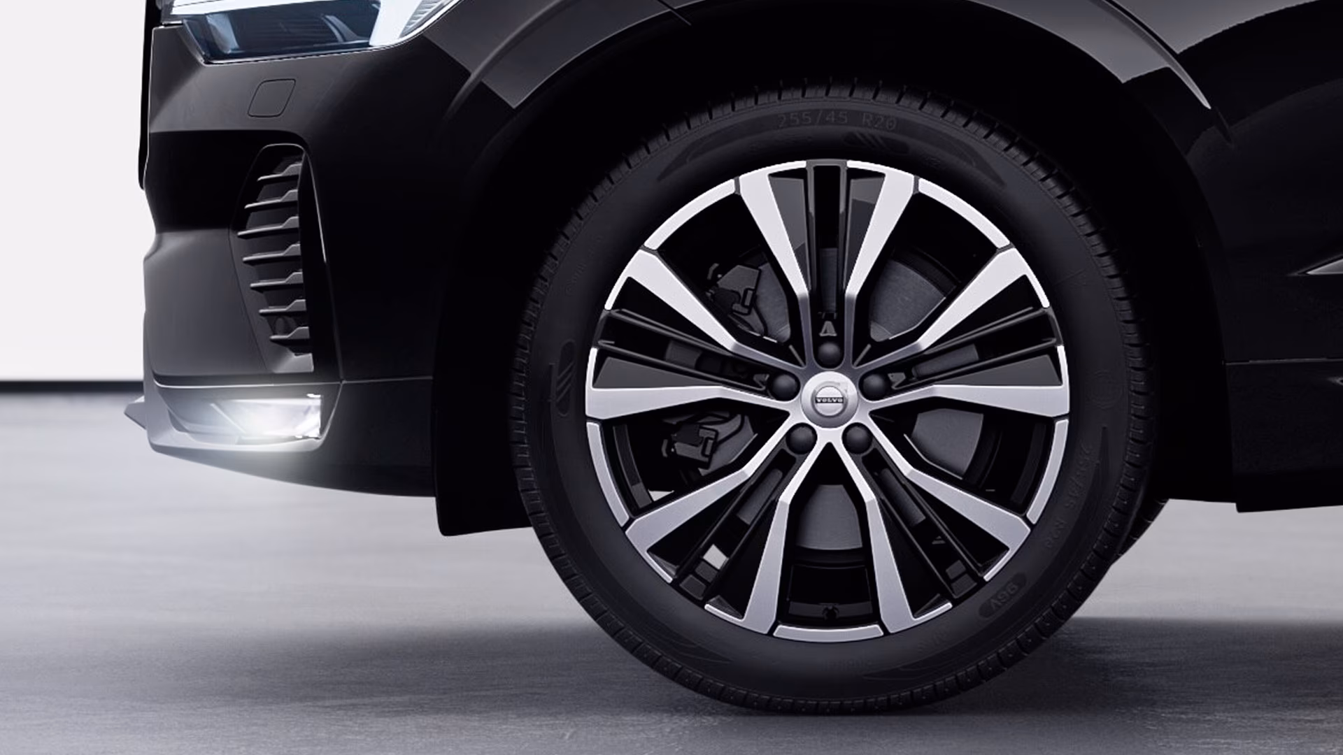 Крупный план переднего колеса и фары автомобиля Volvo, подчеркивающий дизайн легкосплавных дисков.