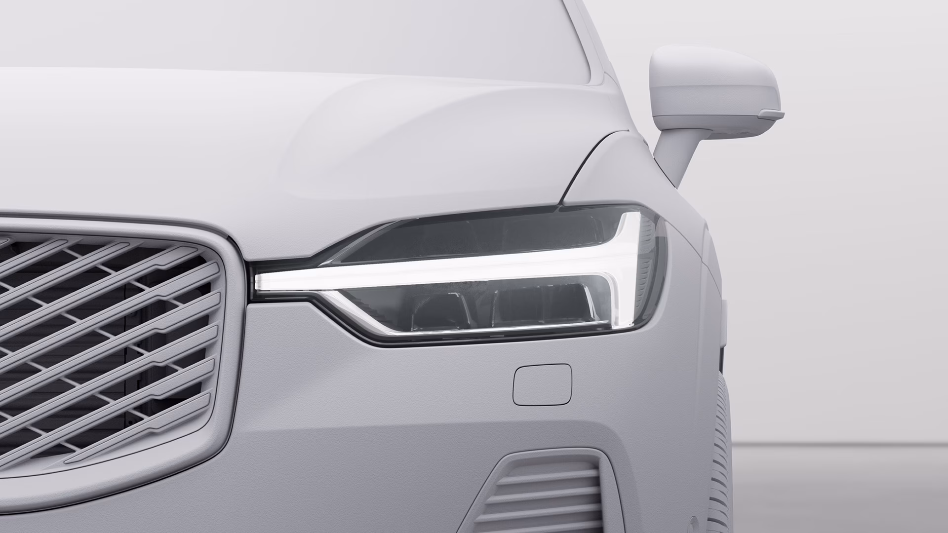 Крупный план передней левой фары, решетки радиатора и бокового зеркала Volvo, демонстрирующие современные детали дизайна.