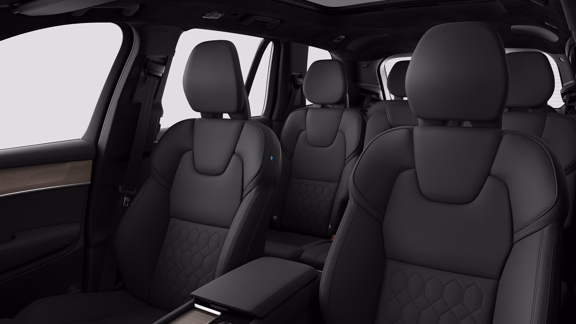 Вид салона автомобиля Volvo с черными кожаными сиденьями с детальной прострочкой и современным просторным дизайном.