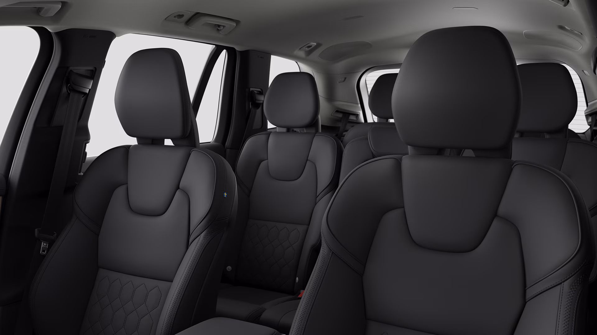 Вид салона автомобиля Volvo с черными кожаными сиденьями в переднем и среднем рядах.