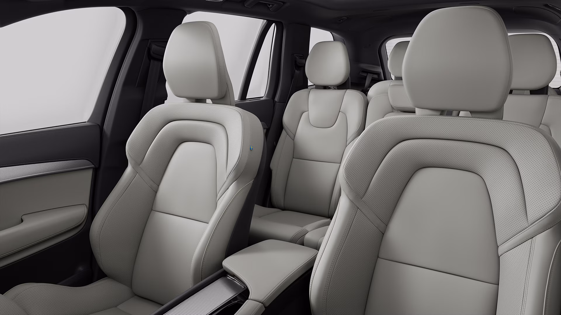 Вид изнутри автомобиля Volvo с тремя рядами светлых кожаных сидений.
