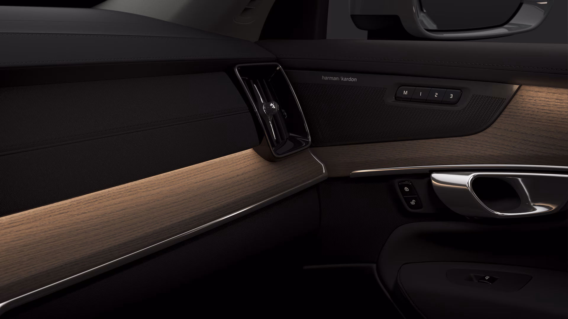 Крупный план салона Volvo с динамиком Harman Kardon, деревянной отделкой и хромированной дверной ручкой.